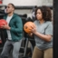 concentrated young diverse trainer and athlete exercising with medicine balls in gym